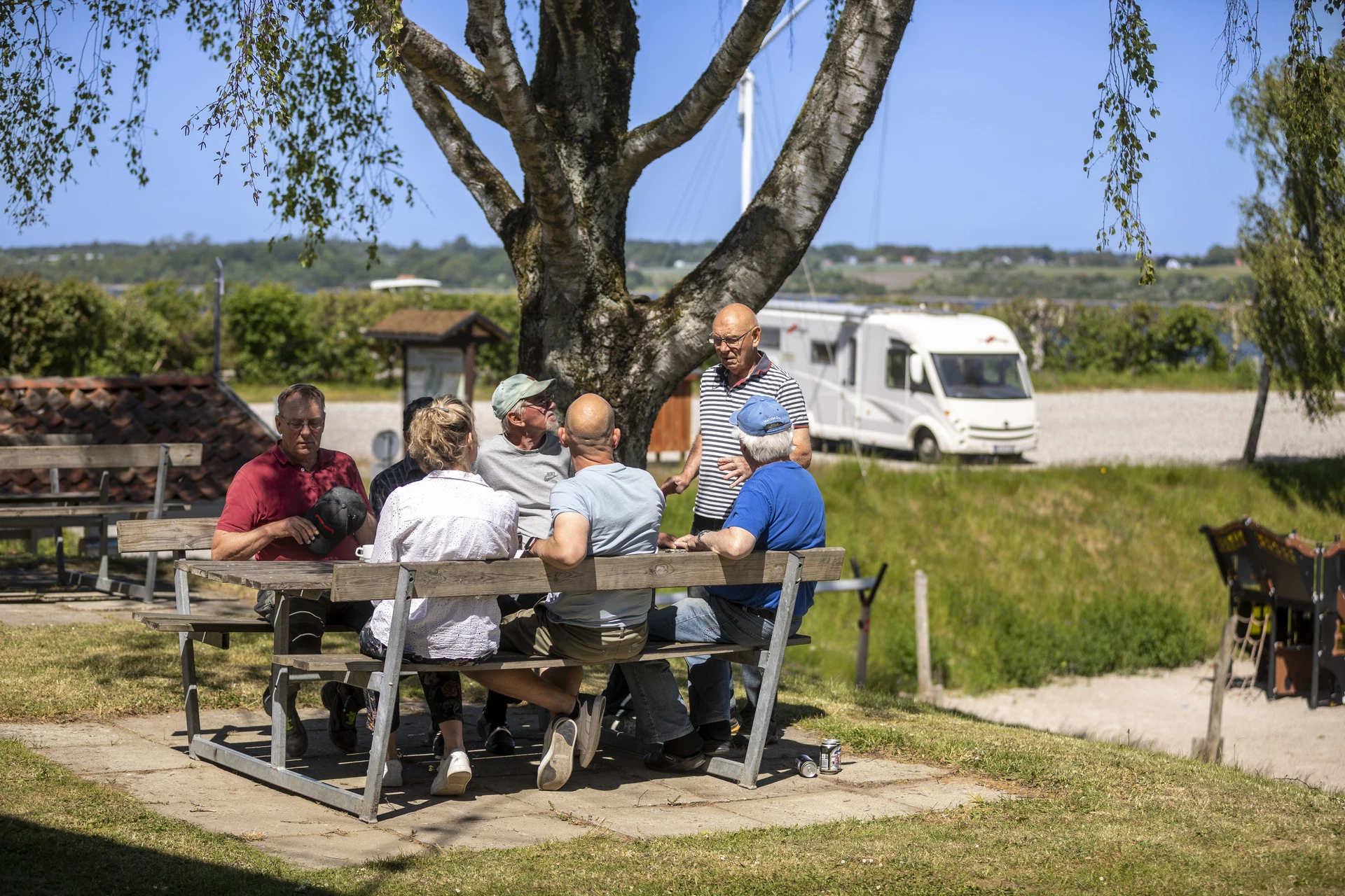 Personer der hygger sig ved en bænk på autocamperpladsen